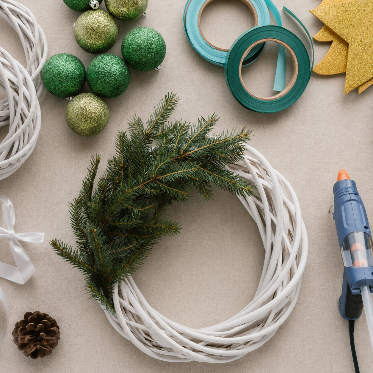 Materials for making a Christmas wreath laid out on a workbench, including evergreen cuttings, a wreath frame, florist wire and decorative accessories.
