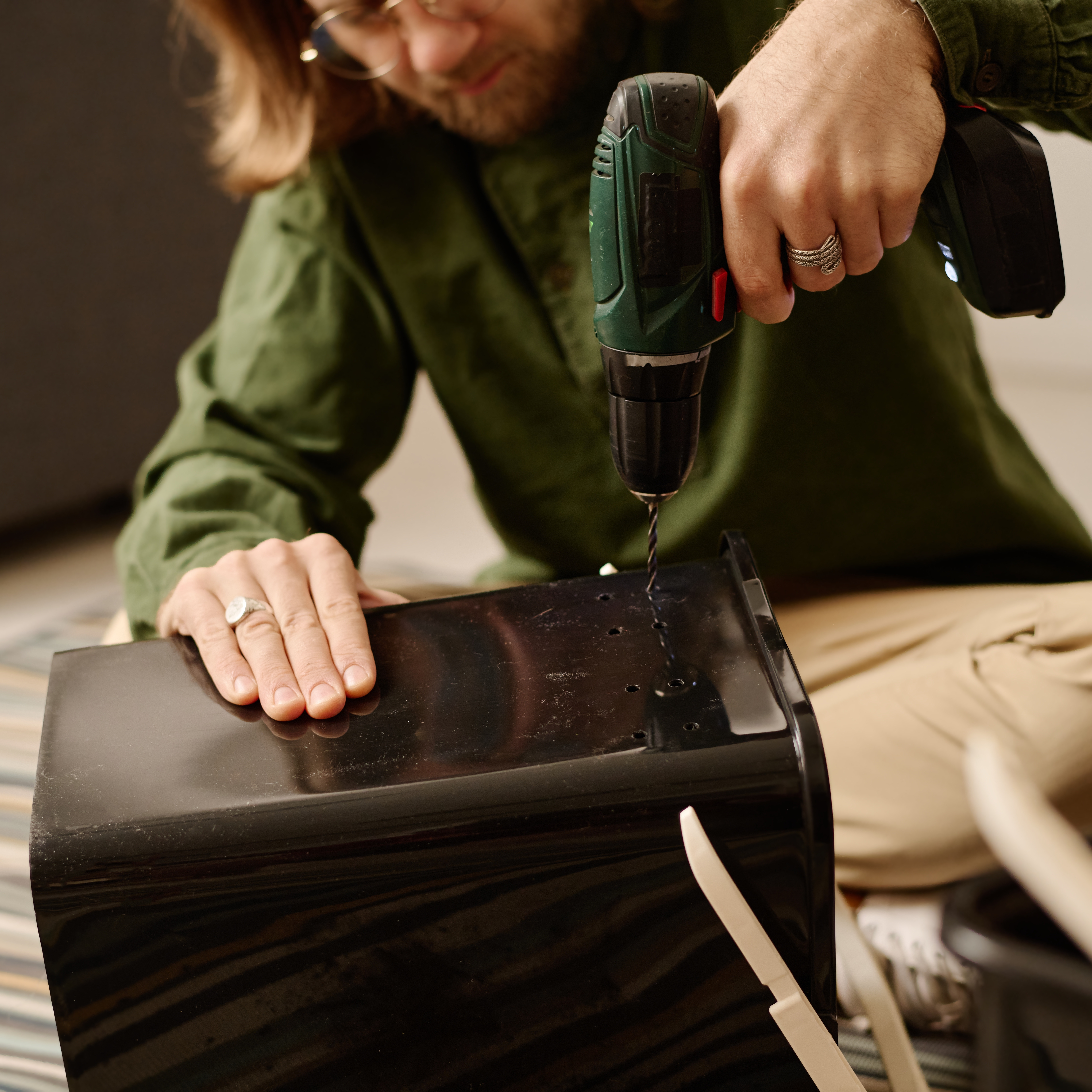 Drilling drainage holes into a recycled plastic container to create a homemade compost bin.