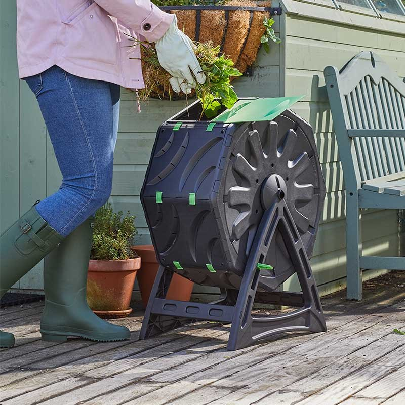 A compost tumbler with garden waste being added.