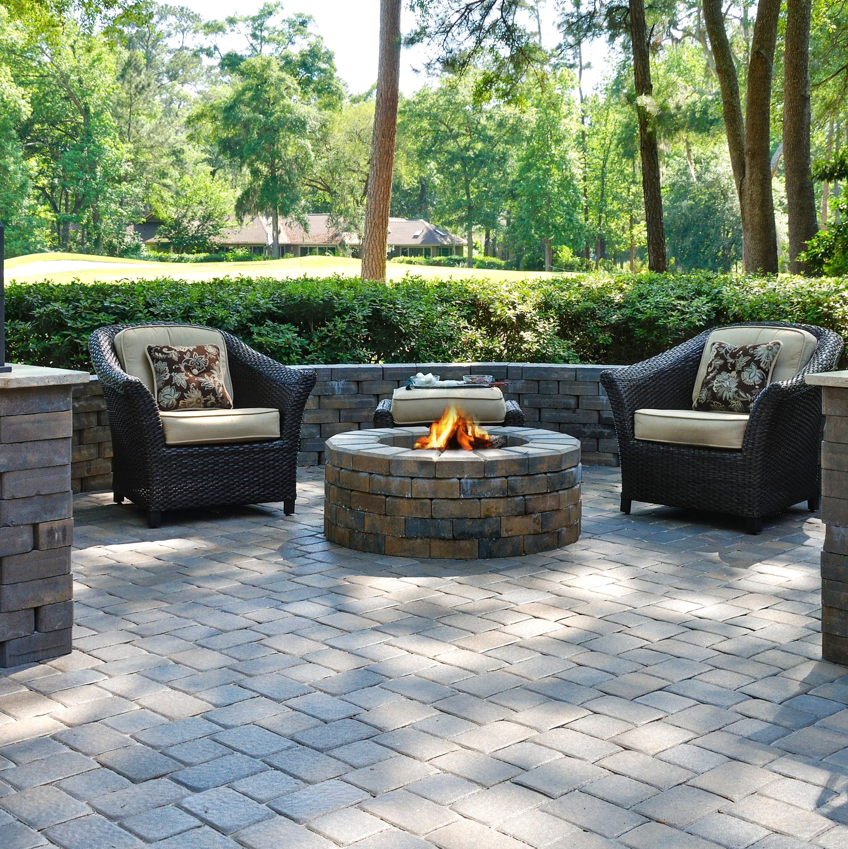 Circular fire pit surrounded by comfortable garden furniture on a patio.