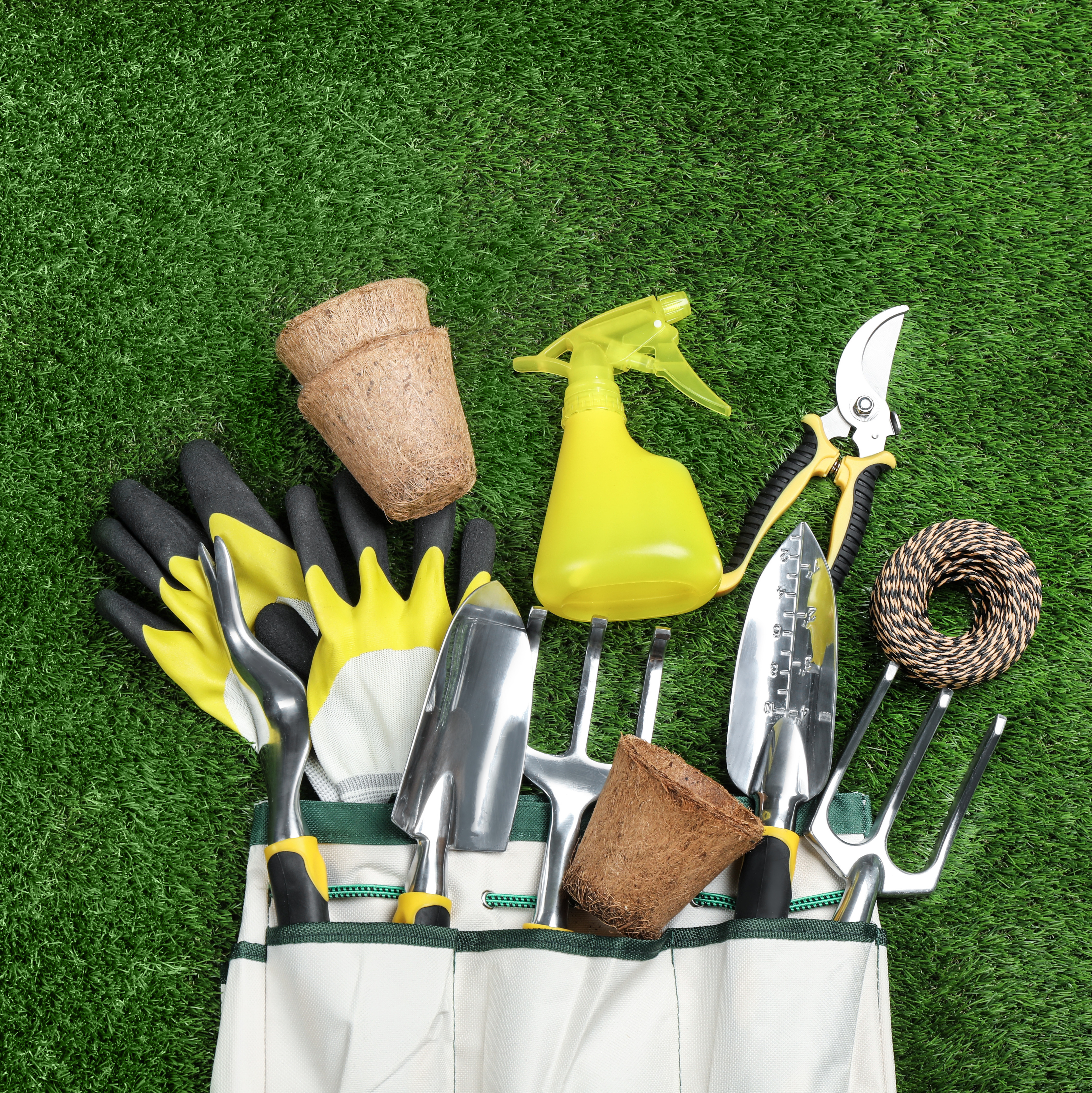 Gardening hand tools and protective gloves arranged on a grass