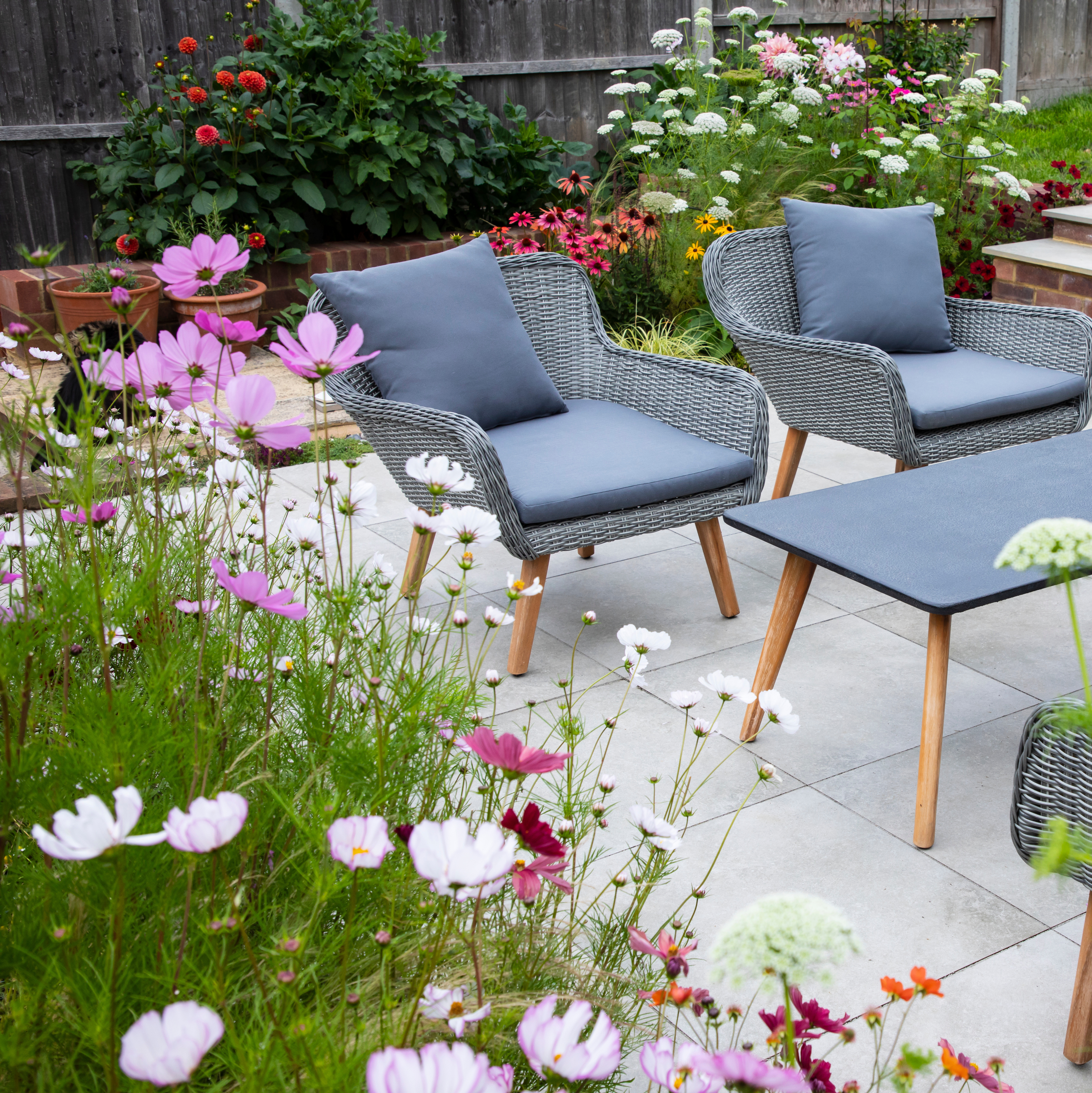 Garden borders surrounding a patio seating area, illustrating how plants shape an outdoor living space.