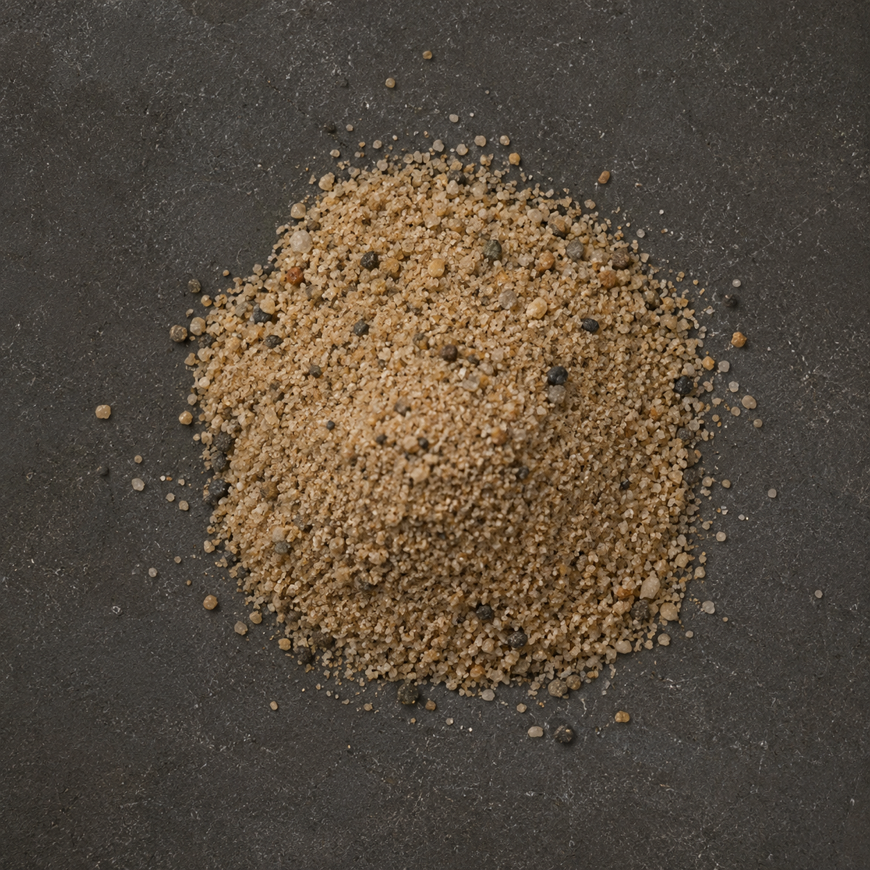 Overhead view of a small pile of coarse horticultural sand on a dark textured surface